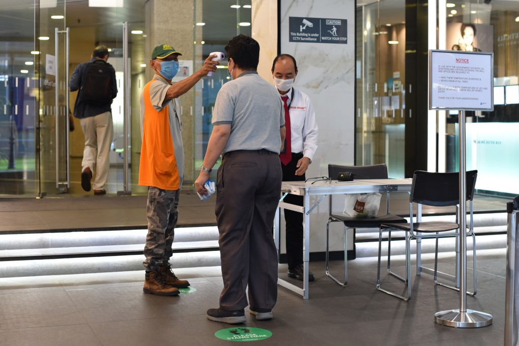 An official uses a thermal scanner to check the temperature of an individual before he can enter a building in Singapore. Photo: AP
