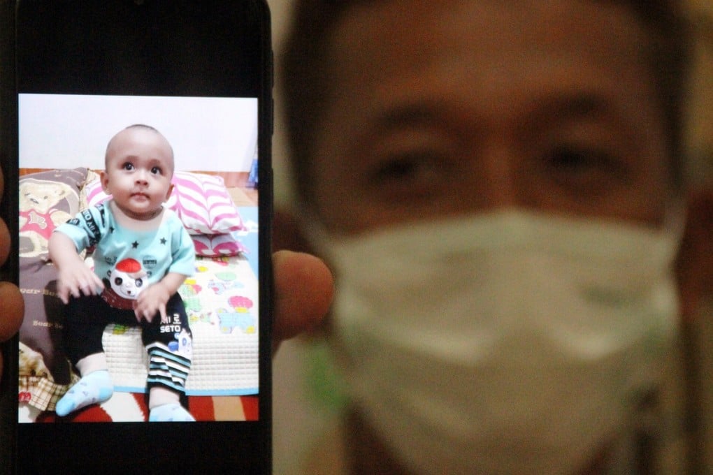 Iyansyah, 45, shows a picture of his child Fahri, who died from coronavirus aged nine months. Photo: Reuters