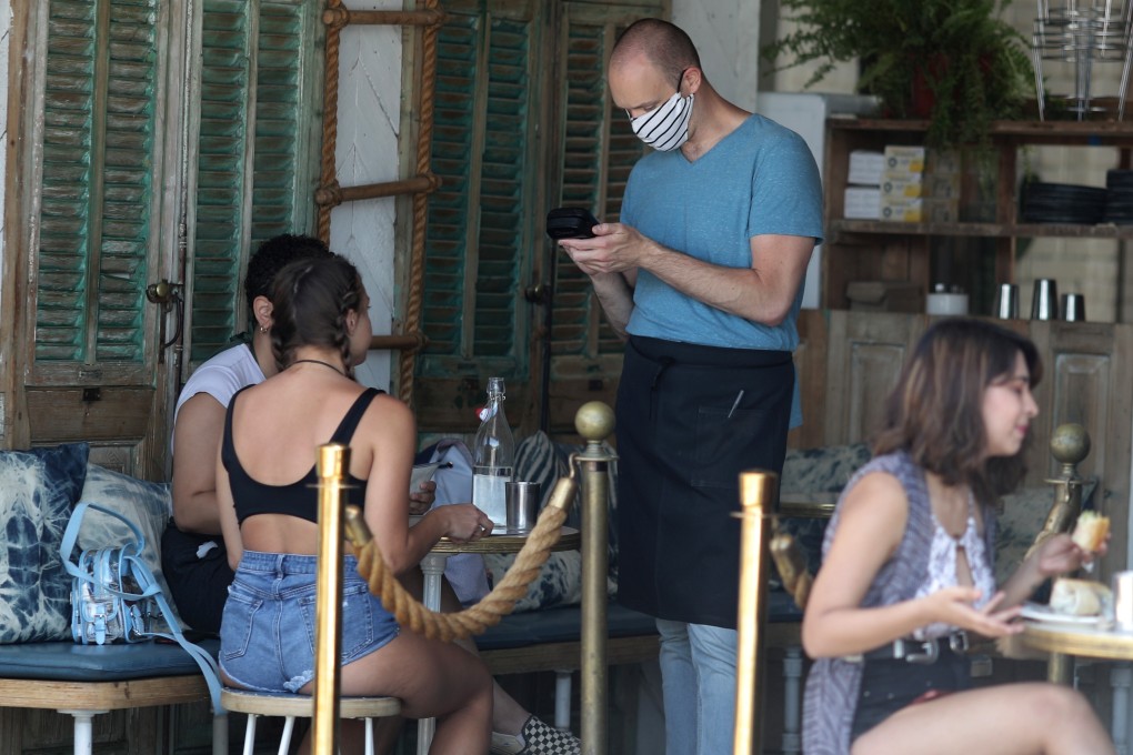 A waiter wears a mask as he serves diners in a cafe in Venice, Los Angeles. California’s hospitalisations have risen in nine of the past 10 days. Photo: Reuters