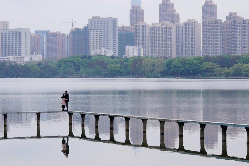 Two people wearing face masks embrace on the East Lake in Wuhan, Hubei province, on March 30. Photo: Reuters