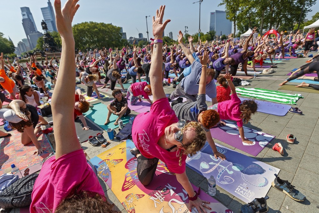 Breast cancer survivors and others strike a yoga pose at an awareness and fundraising event in Philadelphia on May 19, 2019. Photo: TNS