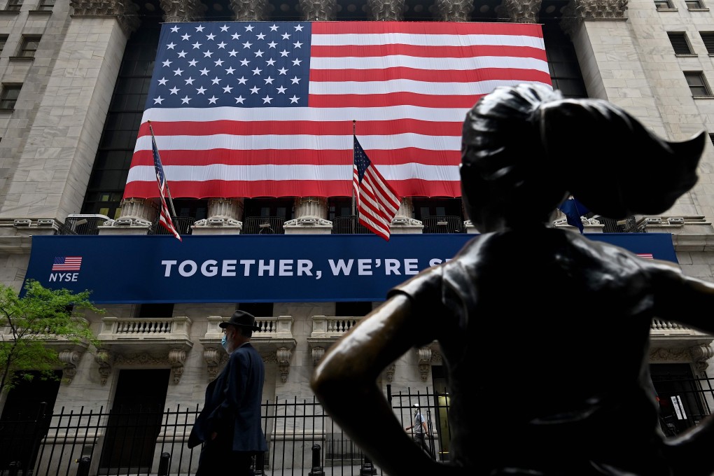 A man passes the New York Stock Exchange on May 26. Stock markets are curiously surging despite corporate earnings being dragged down by the Covid-19 pandemic, suggesting they expect central banks to continue injecting liquidity well into the future. Photo: AFP