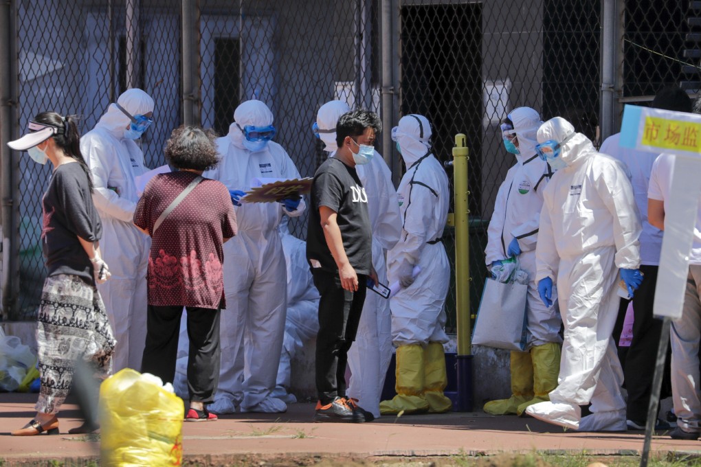 Workers in protective suits check the names of people who were either live near the Xinfadi wholesale market or have visited the market in Beijing. Photo: AP