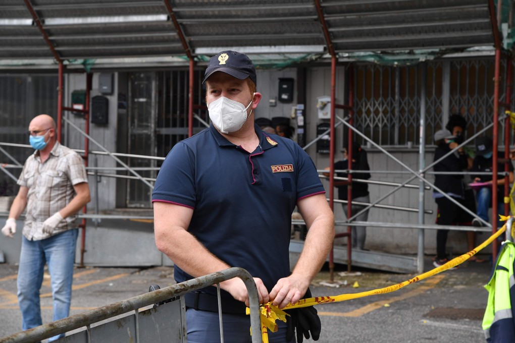 A municipal policeman cordons off the entrance to a building in Rome on Saturday, where at least 17 cases of Covid-19 have been diagnosed recently. Photo: AFP
