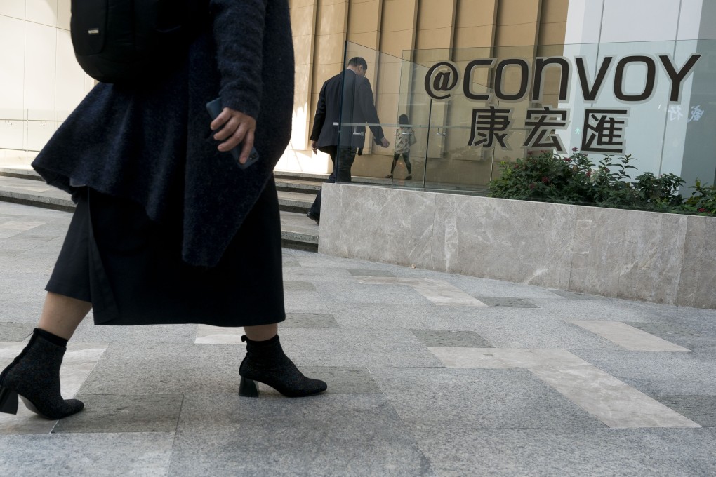 Pedestrians walk past the "@Convoy” sign outside the headquarters of Convoy Global Holdings in Hong Kong in December 2017. Photo: Bloomberg