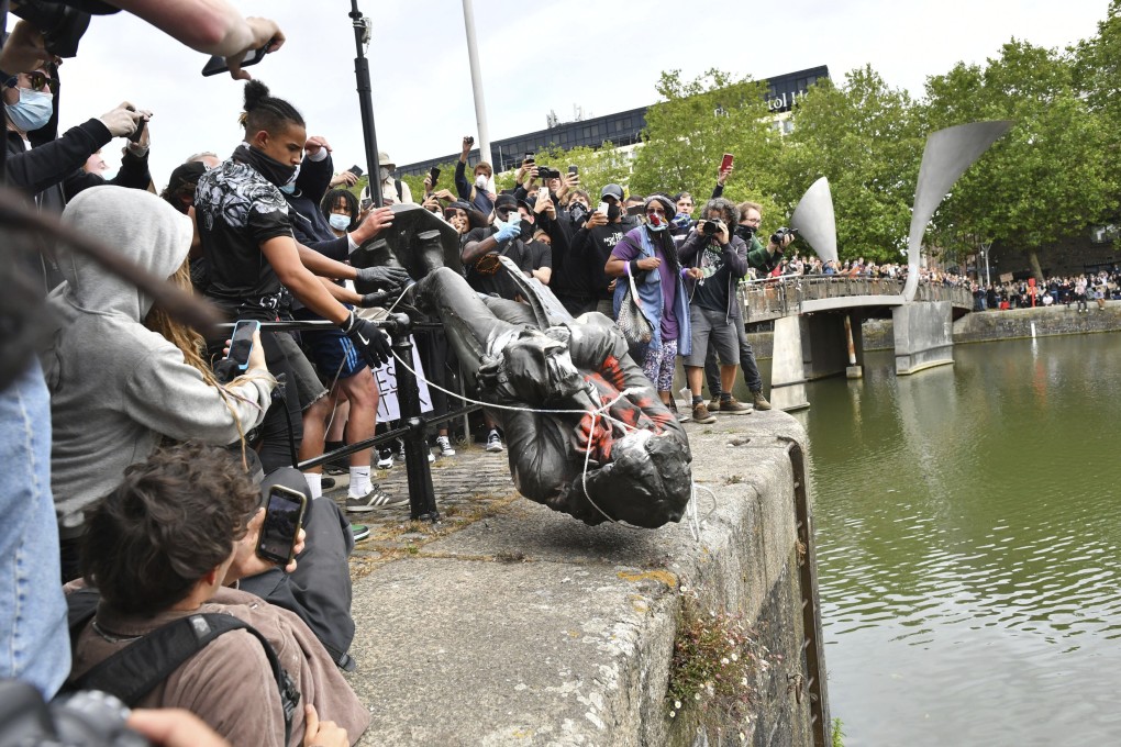 Protesters throw a statue of slave trader Edward Colston into the city harbour during a Black Lives Matter protest rally in Bristol, England, on June 7. Photo: AP