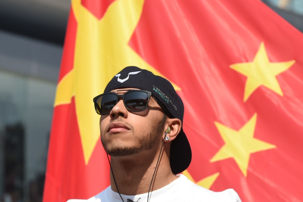 Mercedes AMG Petronas F1 Team's British driver Lewis Hamilton stands by a Chinese flag before the start of the Formula One 2015 Chinese Grand Prix in Shanghai. Photo: AFP