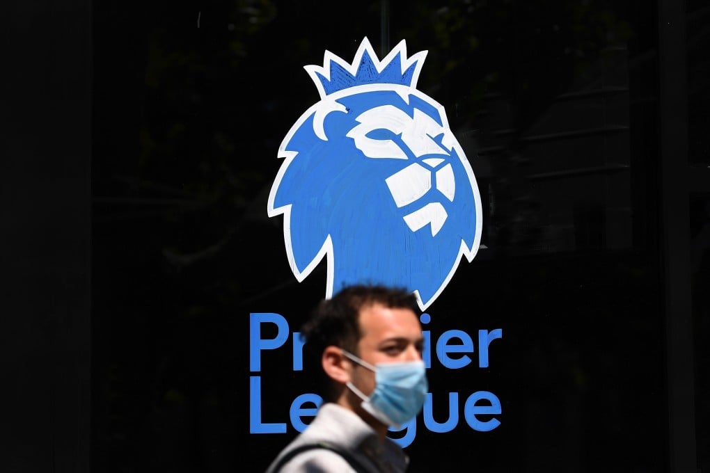 A man wearing a protective mask walks past the English Premier League logo in London. Photo: EPA