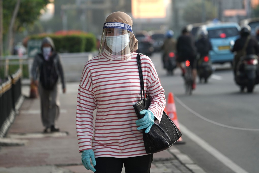 An Indonesian commuter, wearing a protective mask, gloves and face shield, is pictured in Jakarta before returning to work. The country is easing its partial lockdown and reopening the economy, but coronavirus cases are still on the rise. Photo: Bloomberg