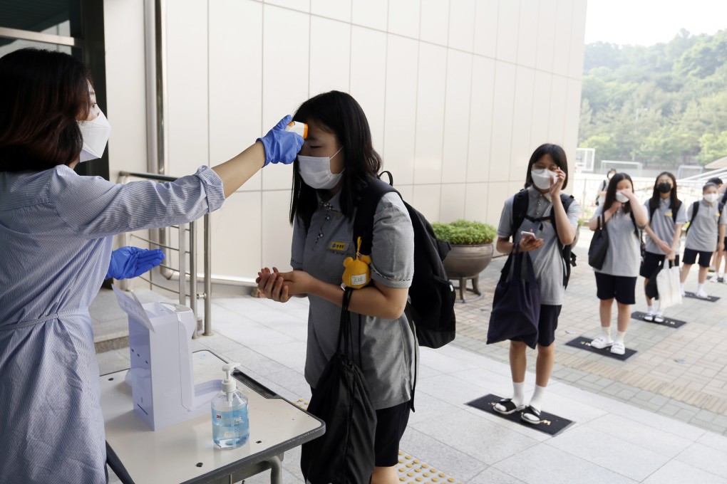 Students stand in a line to have their temperatures checked before entering their classrooms at a school in Chungju, South Korea. Photo: AP