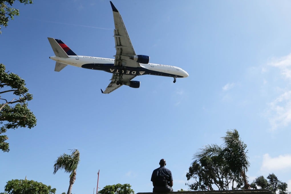 A man watches as a Delta Air Lines plane lands at Los Angeles International Airport in July 2018. Photo: AFP