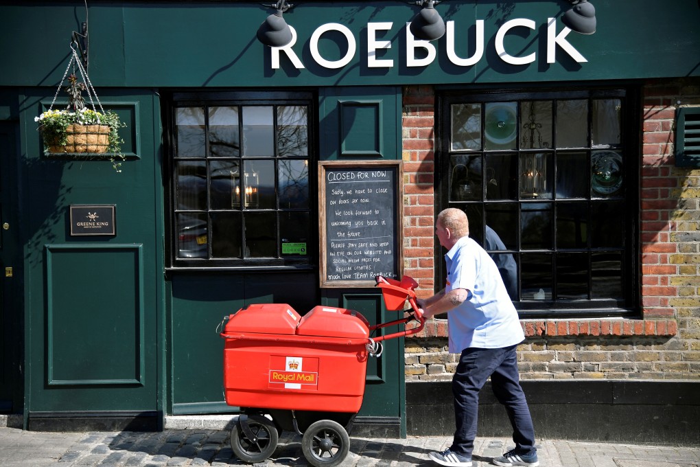 A Royal Mail delivery man looks at a ‘closed’ sign on a pub as he does his rounds amid the pandemic in Richmond, London. Photo: Reuters