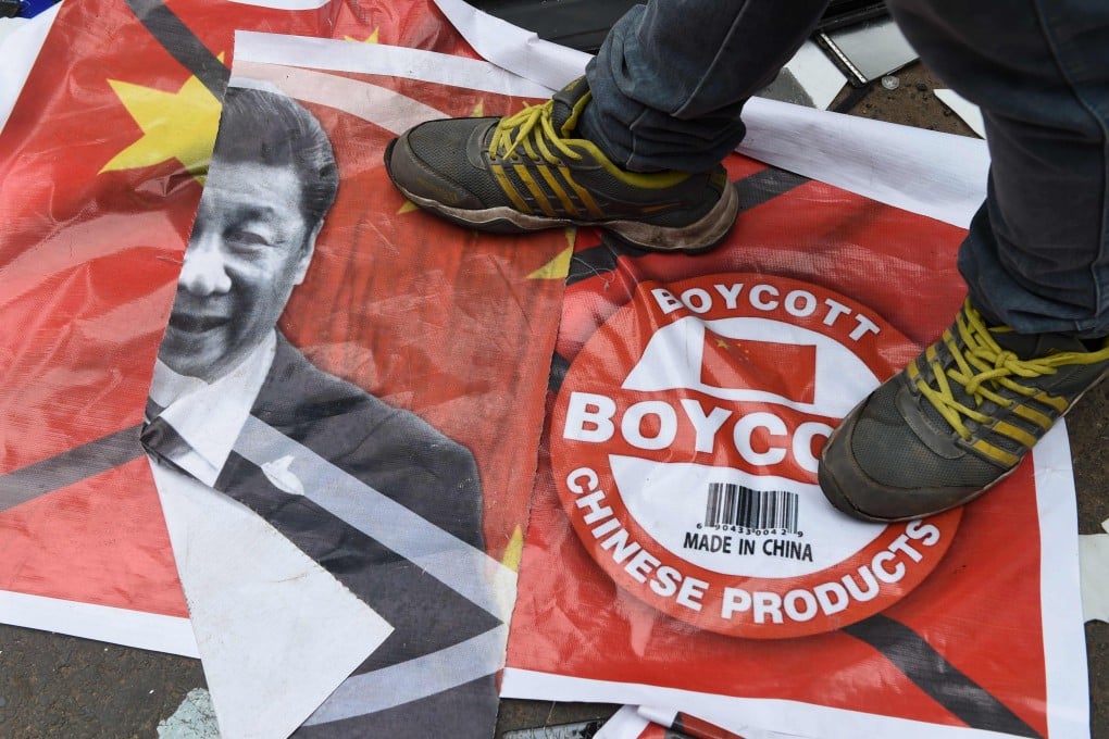 An activist stands on a poster showing Xi Jinping and China’s flag during an anti-China demonstration in Ahmedabad, India, on June 24. Photo: AFP