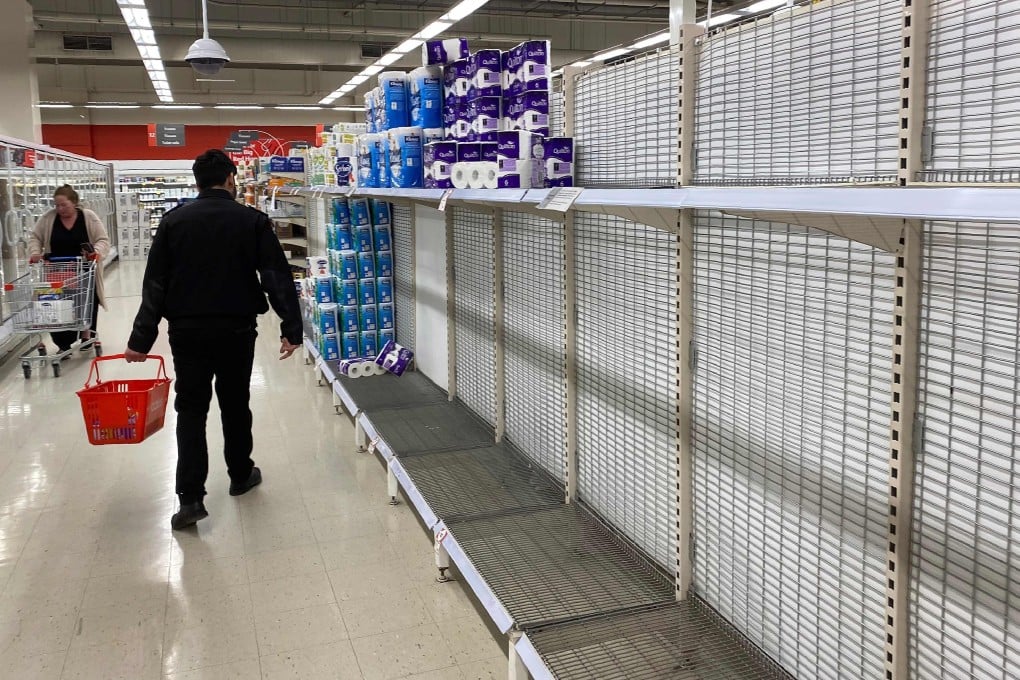 A shopper walks past near-empty shelves of toilet paper at a supermarket in Melbourne. Photo: AFP