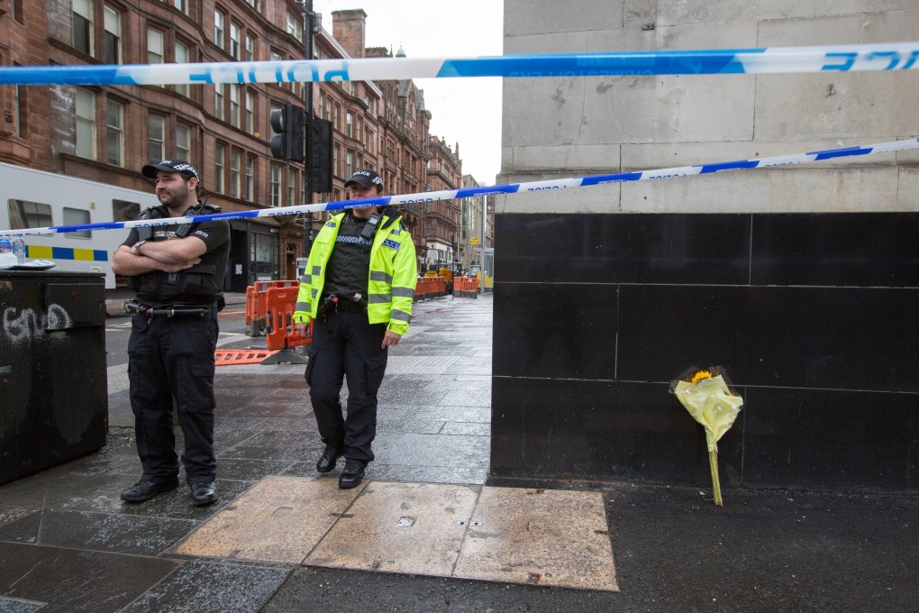 A flower bouquet is propped up against a wall on a street corner next to the Park Inn hotel, where six people were stabbed in Glasgow. Photo: EPA-EFE