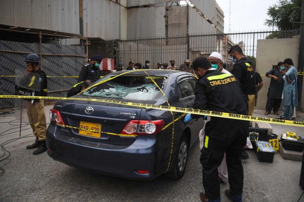 Police investigate a car thought to have been used by the gunmen at the main entrance of the Pakistan Stock Exchange building in Karachi on June 29. Photo: AFP