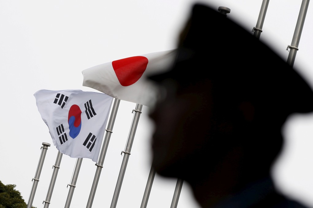 A police officer stands guard near Japanese and South Korean national flags during a 2015 reception to mark the normalising of ties between the two countries. Photo: Reuters