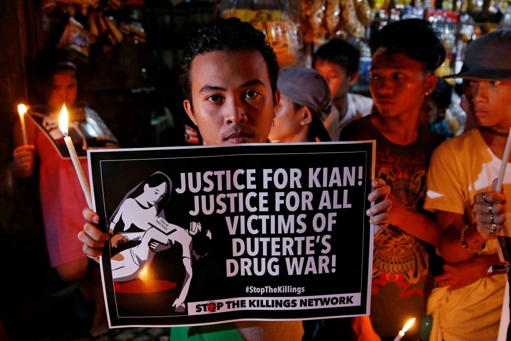 Protesters and residents hold lighted candles and placards at the wake of Kian delos Santos, a 17-year-old high school student who was among the minors killed by authorities. Photo: Reuters