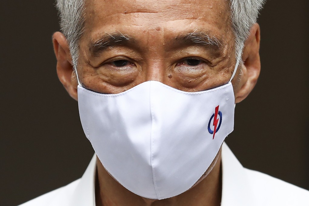 Singapore’s Prime Minister and People’s Action Party leader Lee Hsien Loong wears a mask adorned with his party’s logo as he waits to field questions from the media on June 30. Photo: AP