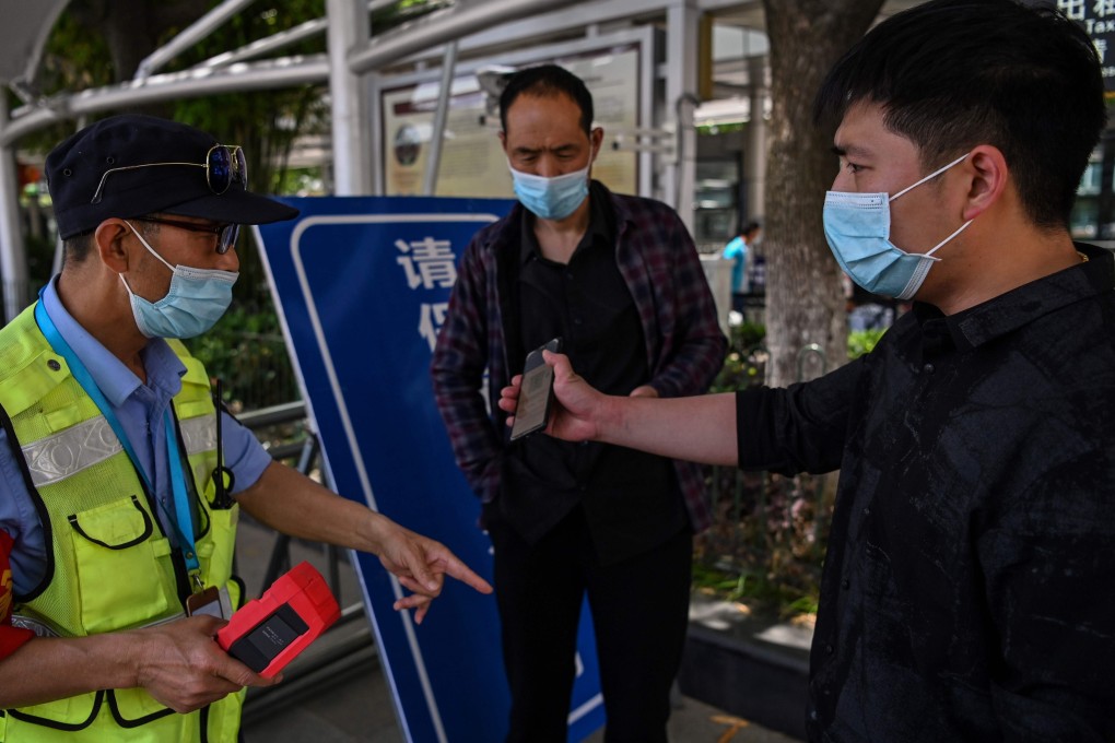 A worker checks passengers’ body temperatures and a health code on their phones before they take a taxi after arriving at Hankou railway station in Wuhan. Technology has been crucial to getting around in China during the pandemic but not everyone is able to take part in this digitally-driven society. Photo: AFP