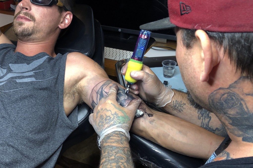 Tattoo artist Alexander Lawrence (right) covers a tattoo that contained the image of a swastika on the arm of Dylan Graves in Bellows Falls in the US state of Vermont. Photo: AP
