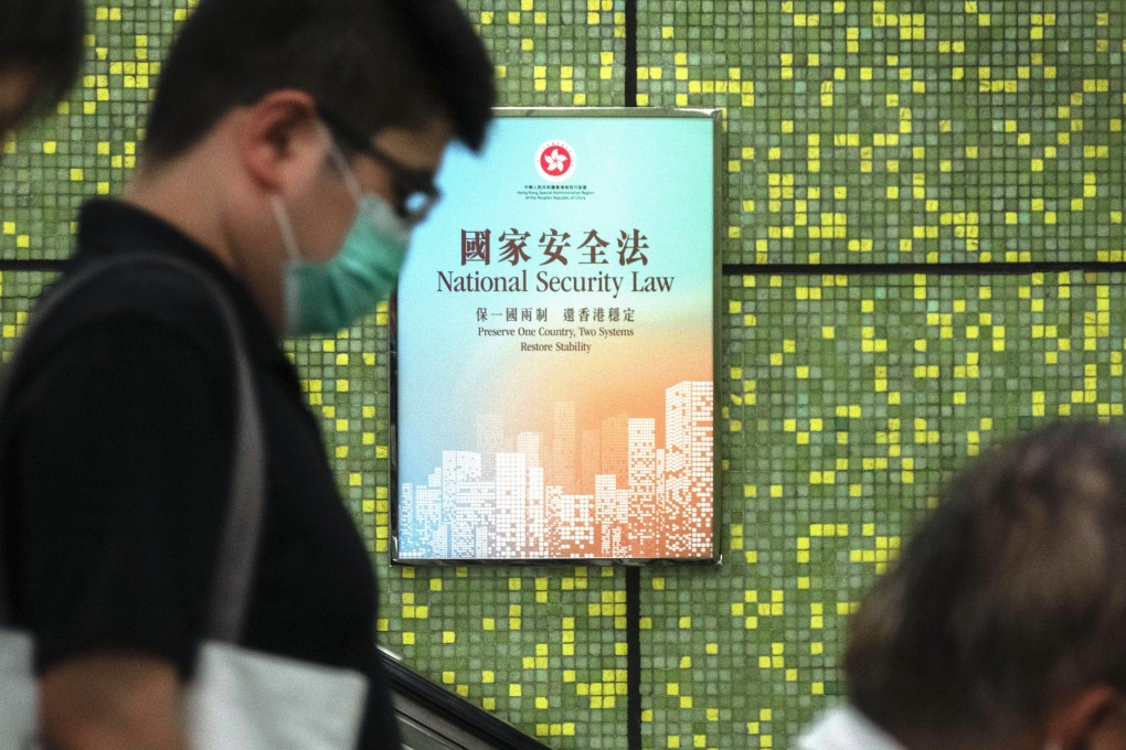 Pedestrians ride an escalator past a poster about Hong Kong’s new national security law. Photo: Bloomberg