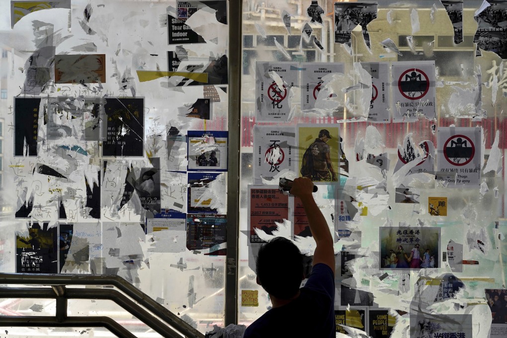 A pro-China activist cleans up posters and labels with messages on a “Lennon wall” of anti-government posters in Causeway Bay on September 21, 2019. Photo: AP