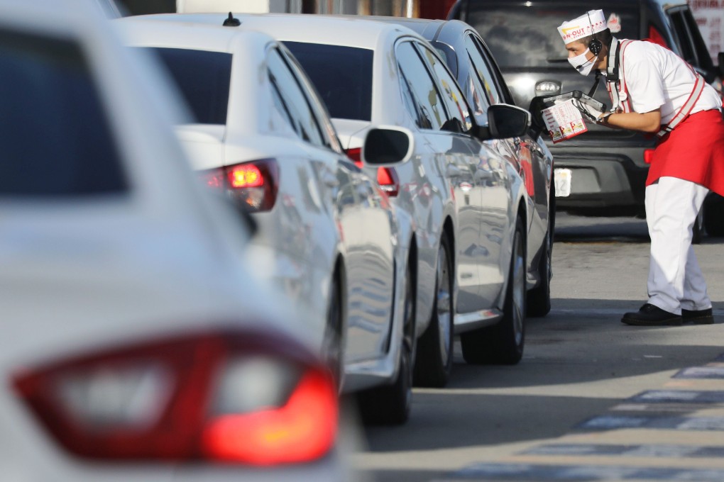 A worker in a face mask takes orders from motorists in the drive-through lane at a burger restaurant on July 1 in Los Angeles, California. California governor Gavin Newsom has ordered indoor dining restaurants to close again for at least three weeks amid a surge in new coronavirus cases. Photo: AFP