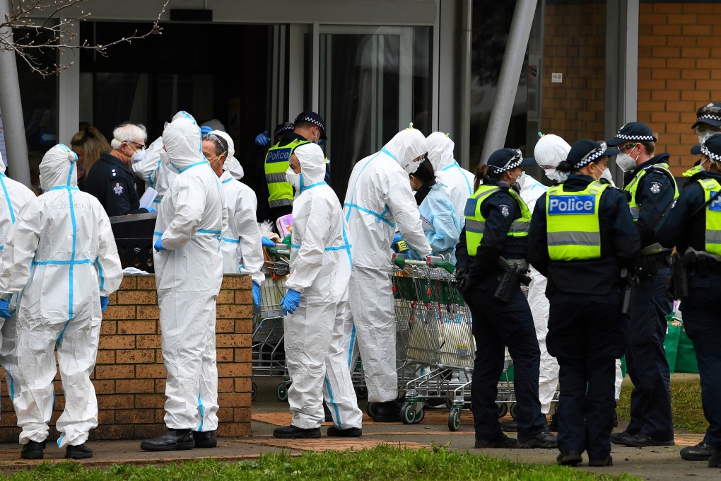 Firefighters dressed in personal protective equipment prepare to distribute food throughout a Melbourne housing estate, locked down in response to an outbreak of coronavirus. Photo: Reuters