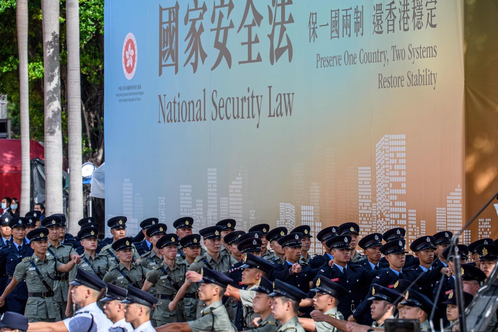 Disciplined forces march next to a banner supporting the new national security law, at the end of a flag-raising ceremony to mark the 23rd anniversary of Hong Kong’s handover in Wan Chai on July 1. Photo: AFP