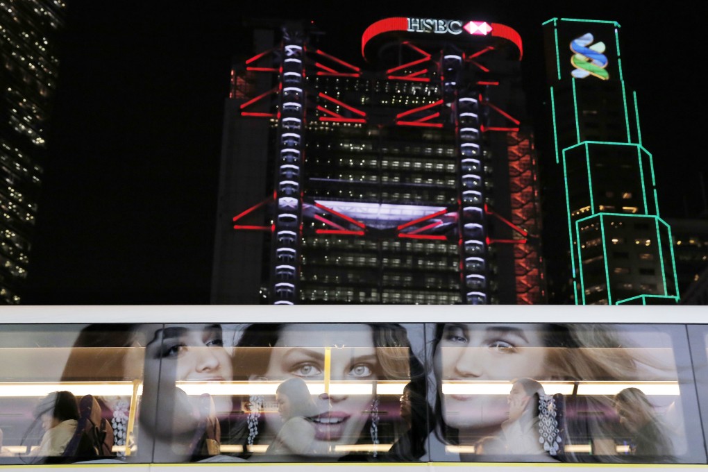 An advert is reflected on a bus window, with the Hong Kong headquarters of HSBC and Standard Chartered in the background. Photo: AP