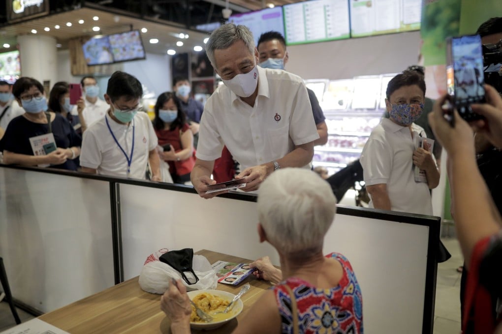 Singapore Prime Minister Lee Hsien Loong, centre, speaks to a woman at a food court during a campaign walkabout on July 1. Photo: EPA