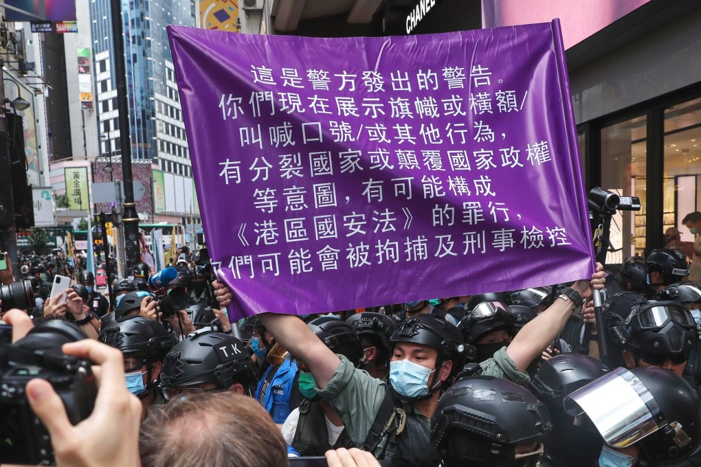 A police officer in riot gear holds up a purple flag warning anti-government protesters they may be violating the national security law during an illegal demonstration in Causeway Bay on July 1, the 23rd anniversary of the establishment of the Hong Kong Special Administrative Region. Photo: Sam Tsang