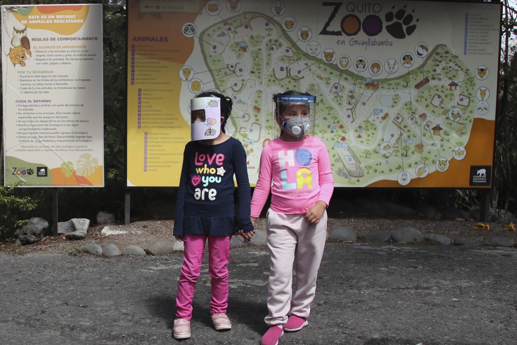 Girls wearing face shields wait for their parents before entering a zoo on the outskirts of Quito, Ecuador on Wednesday. Photo: AP