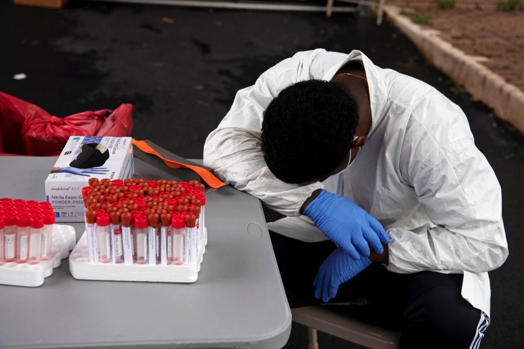 An overheated health care worker takes a break as people join long queues in their vehicles for Covid-19 testing in Houston, Texas, on Tuesday. Photo: Reuters