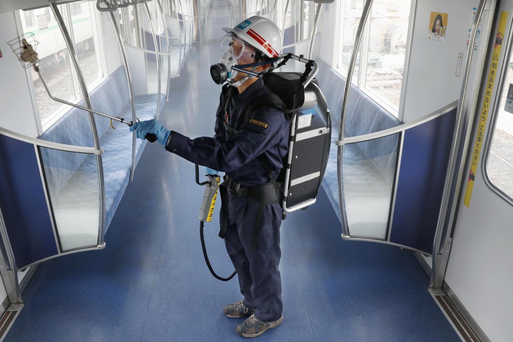 A Tokyo Metro worker, wearing goggles and protective mask, sprays antivirus inside a passenger car at its depot. Photo: Kyodo