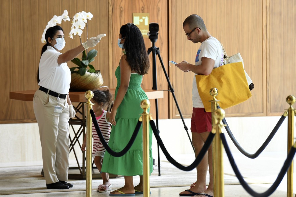 A member of staff checks the temperature of a tourist at the Mandarin Oriental Jumeira on July 9. Dubai reopened its doors to international visitors last week in the hope of reviving its tourism industry after a nearly four-month closure. Photo: AFP
