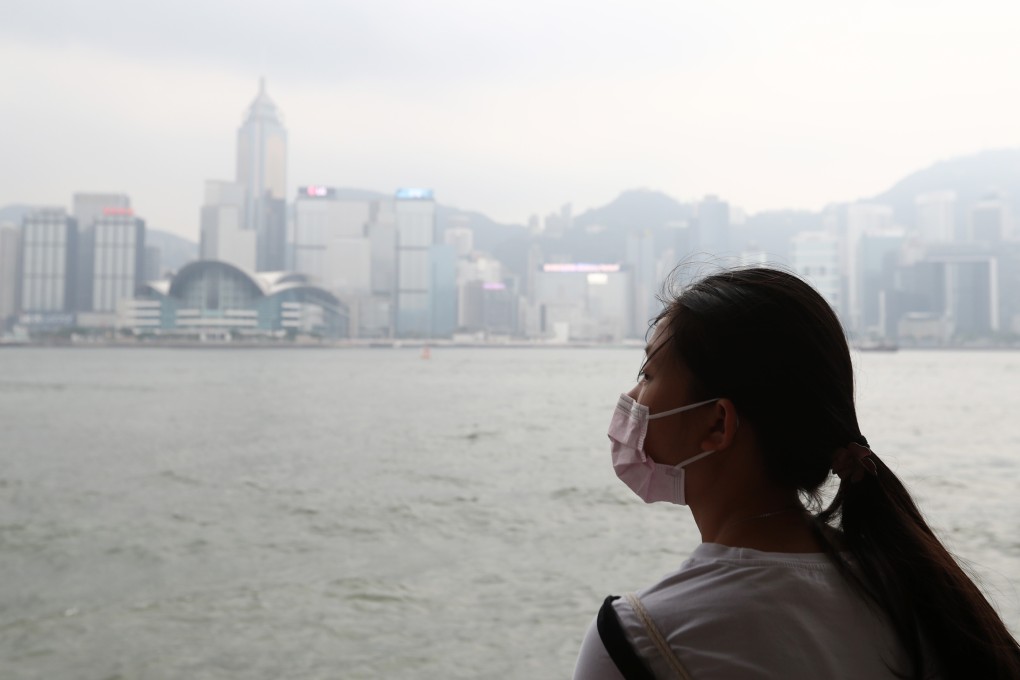A woman wearing a face mask looks across Victoria Harbour as the Hong Kong skyline is obscured by smog on August 26, 2018. Photo: Nora Tam
