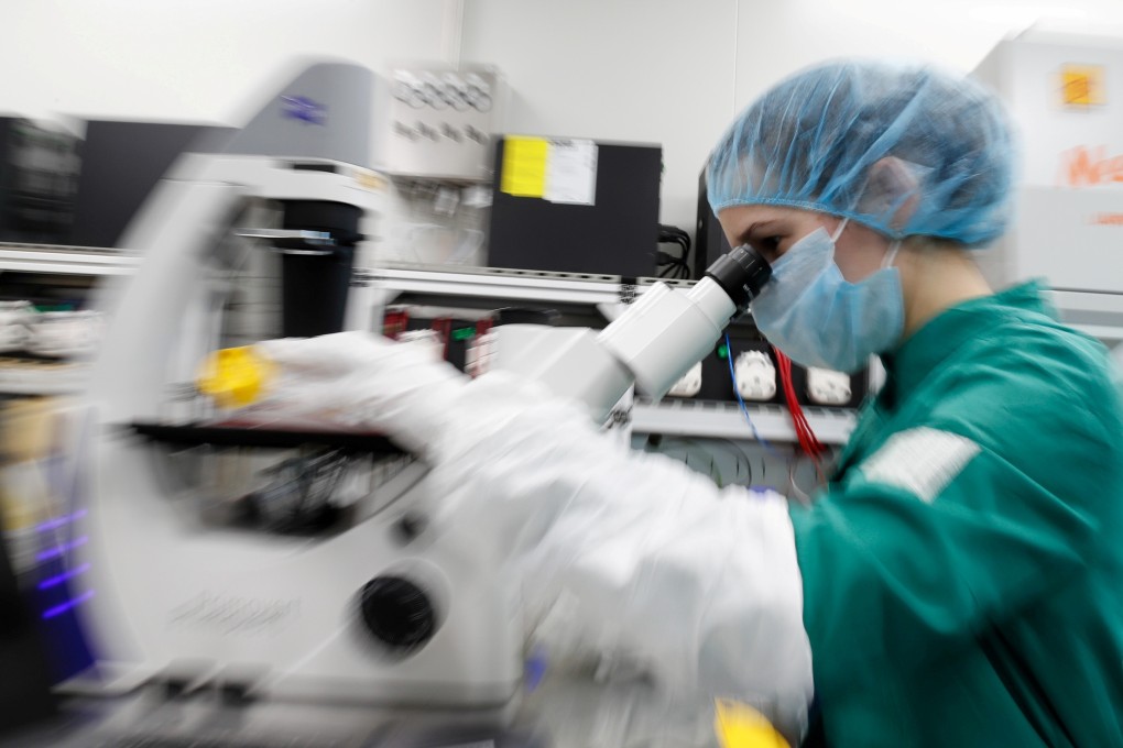 A scientist examines infected cells under a microscope during research for a vaccine in a laboratory. Photo: Reuters
