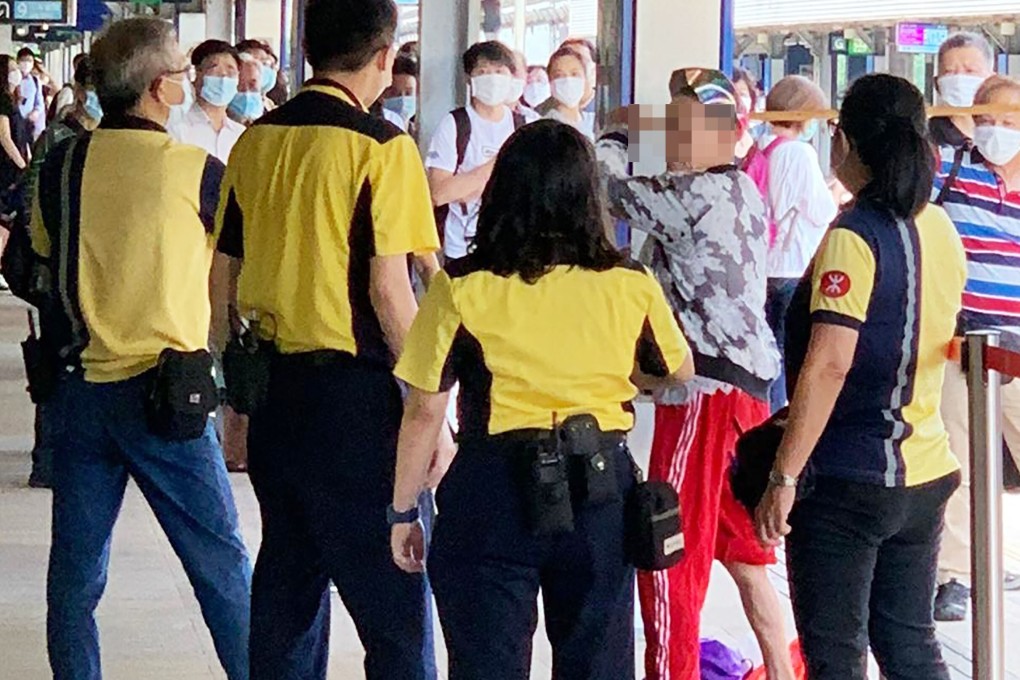 MTR staff at Tai Wan station surround a man who holds a stick over his head after refusing to wear a mask. Photo: Handout