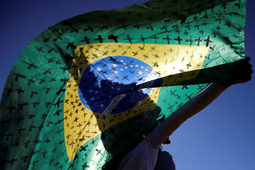 An activist holds a Brazilian flag painted with crosses symbolising people who died from Covid-19 in front of the National Congress in Brasilia on Tuesday. Photo: Reuters