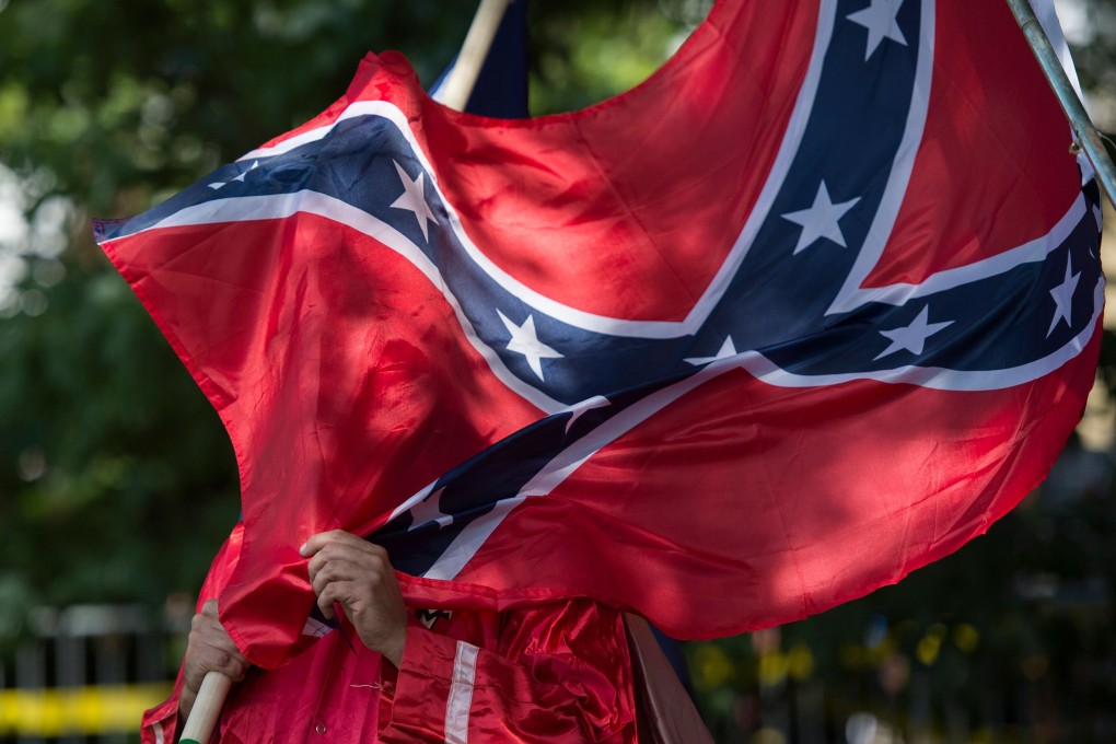 A member of the Ku Klux Klan holds a Confederate flag over his face during a rally. Photo: AFP