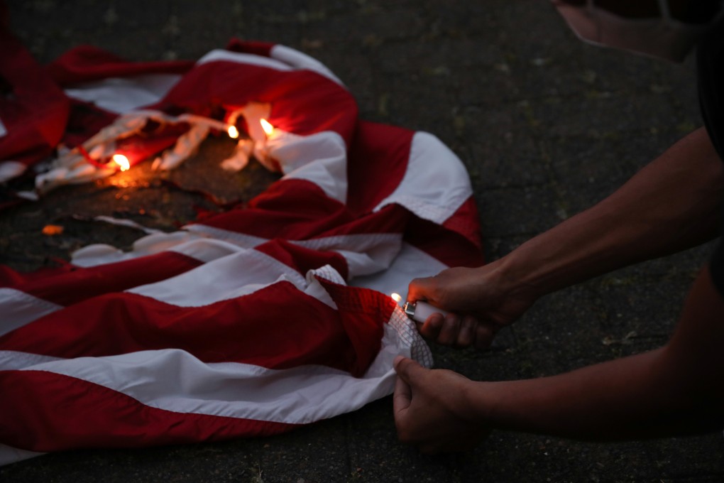 A demonstrator burns a flag during a protest against racial inequality in Portland, Oregon. City and state officials want federal police to leave the city. Photo: Reuters