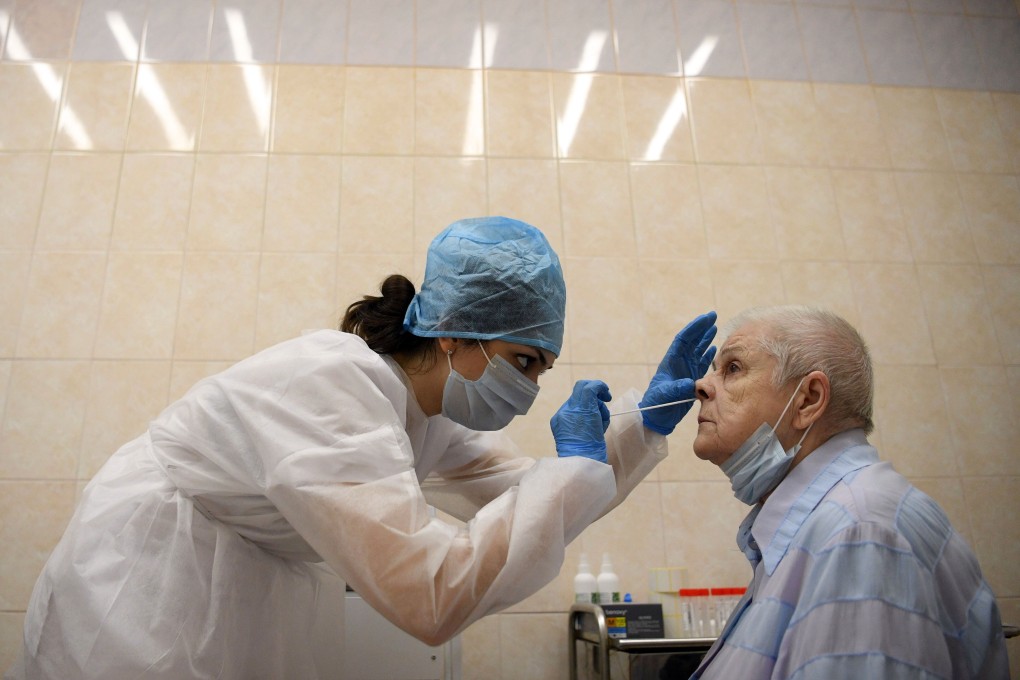 A medical worker wearing protective equipment takes a swab from a woman at a medical facility in Moscow. Photo: AFP
