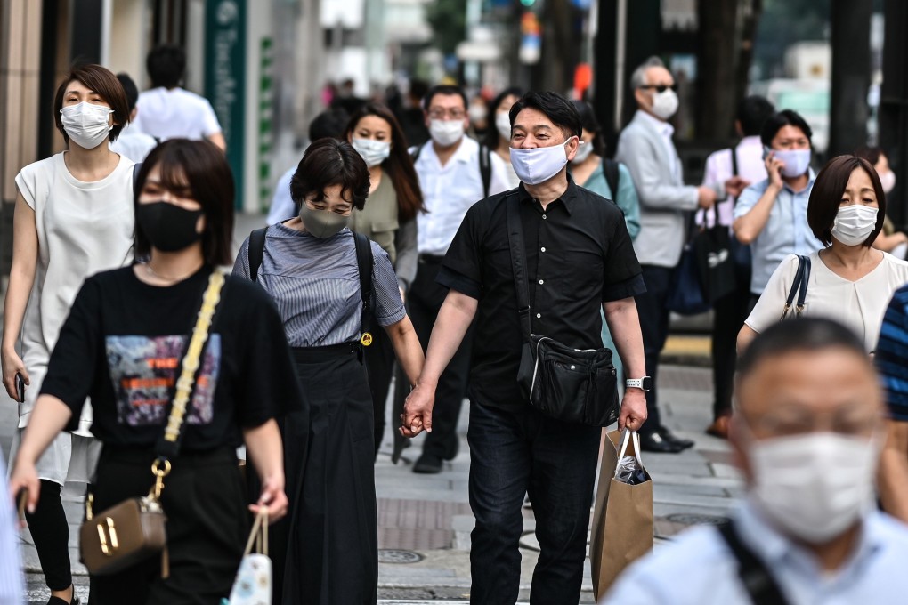 People wearing face masks walk in a street in Tokyo on July 20, as Japan’s death toll eclipsed 1,000, and 168 new cases were recorded in the capital. Photo: AFP