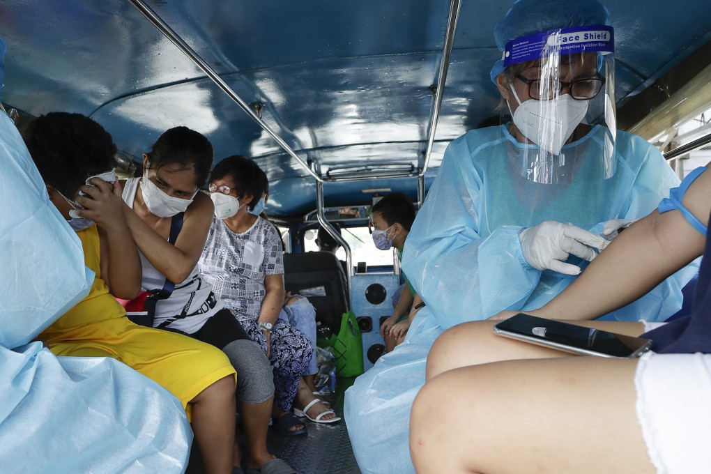 Health workers collect blood samples inside a jeepney bus at a free Covid-19 drive-through testing facility in Manila. Photo: AP
