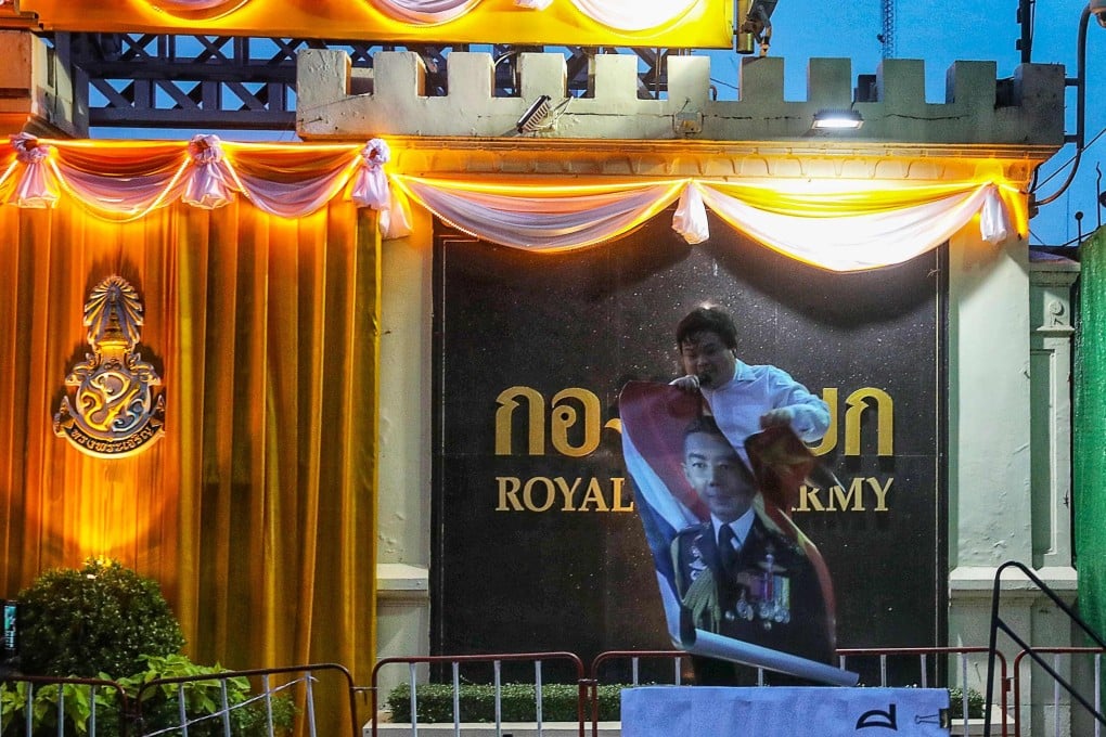 A protester tears a poster of Thai army chief General Apirat Kongsompong during a demonstration in front of the army headquarters in Bangkok on Monday. Photo: AFP