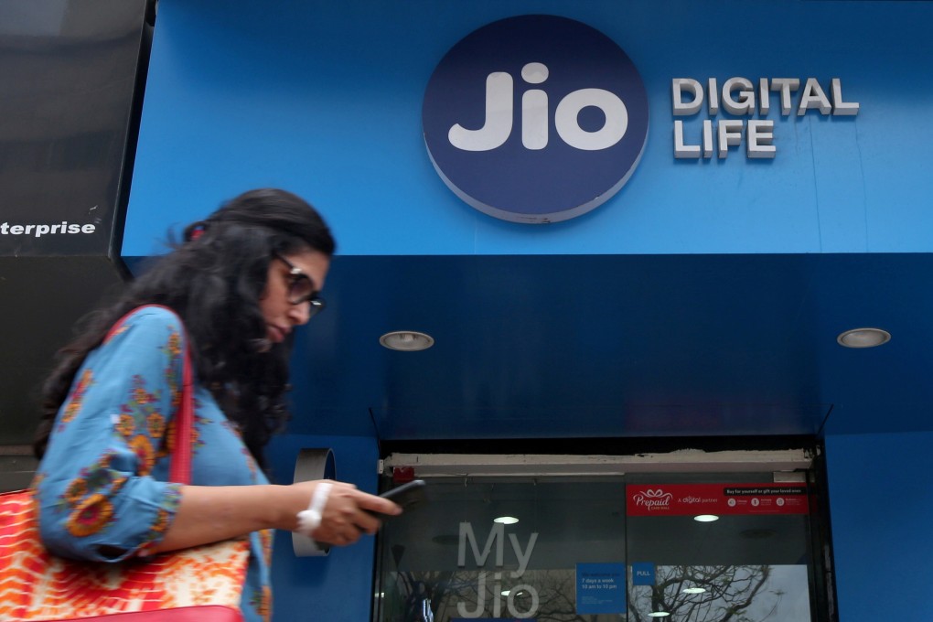 A woman checks her mobile phone as she walks past a mobile store of Reliance Industries' Jio telecoms unit, in Mumbai, India, July 11, 2017. Photo: Reuters