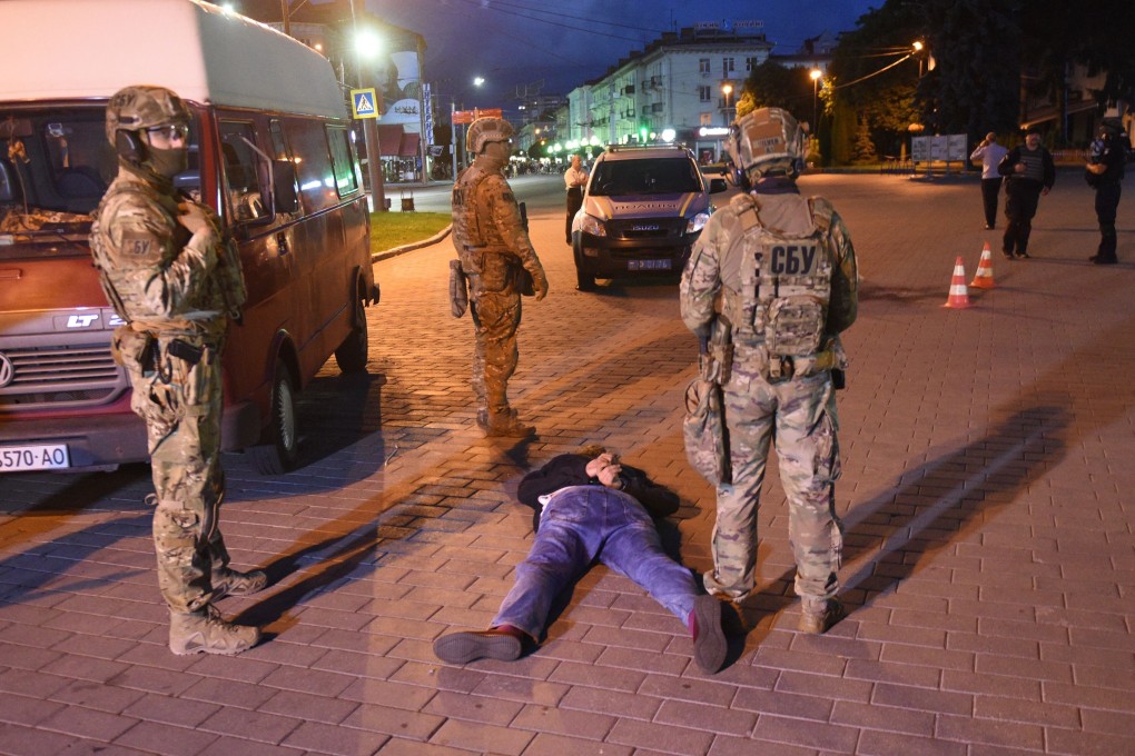 A suspected hostage-taker lies on the ground after being detained by law enforcement officers in Lutsk on Tuesday. Photo: AFP