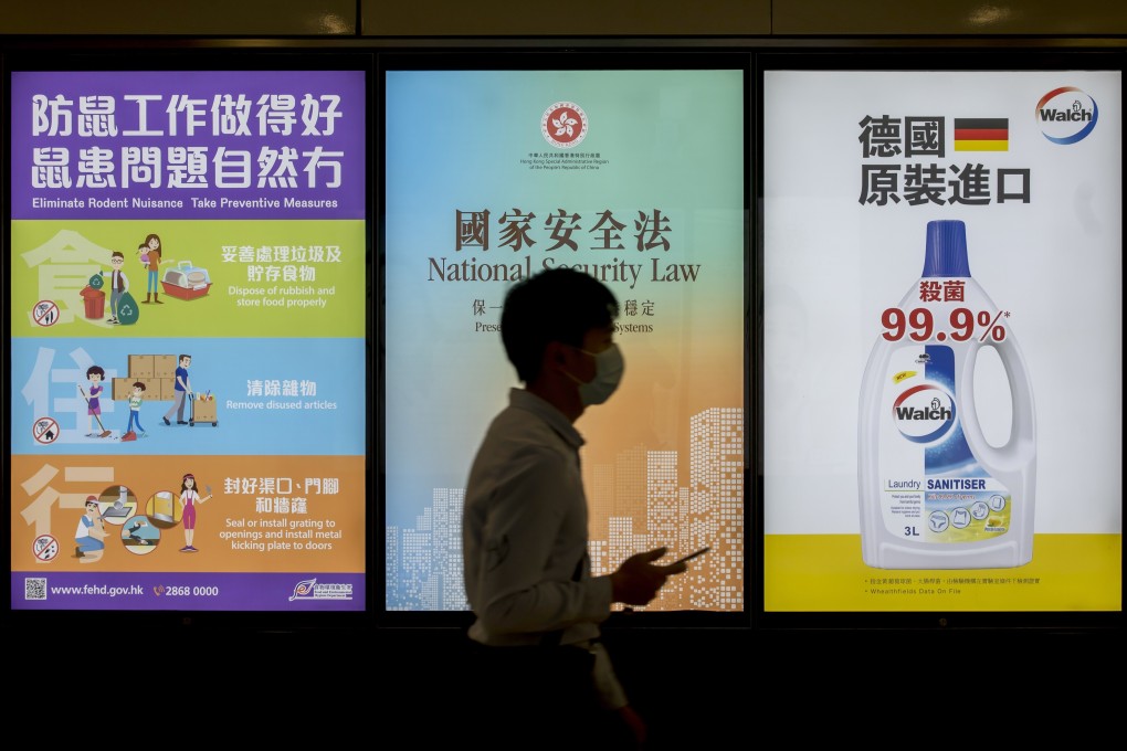 A pedestrian in Hong Kong, wearing a mask as the city battles a coronavirus outbreak, passes a government-sponsored advertisement for the national security law. Photo: Bloomberg